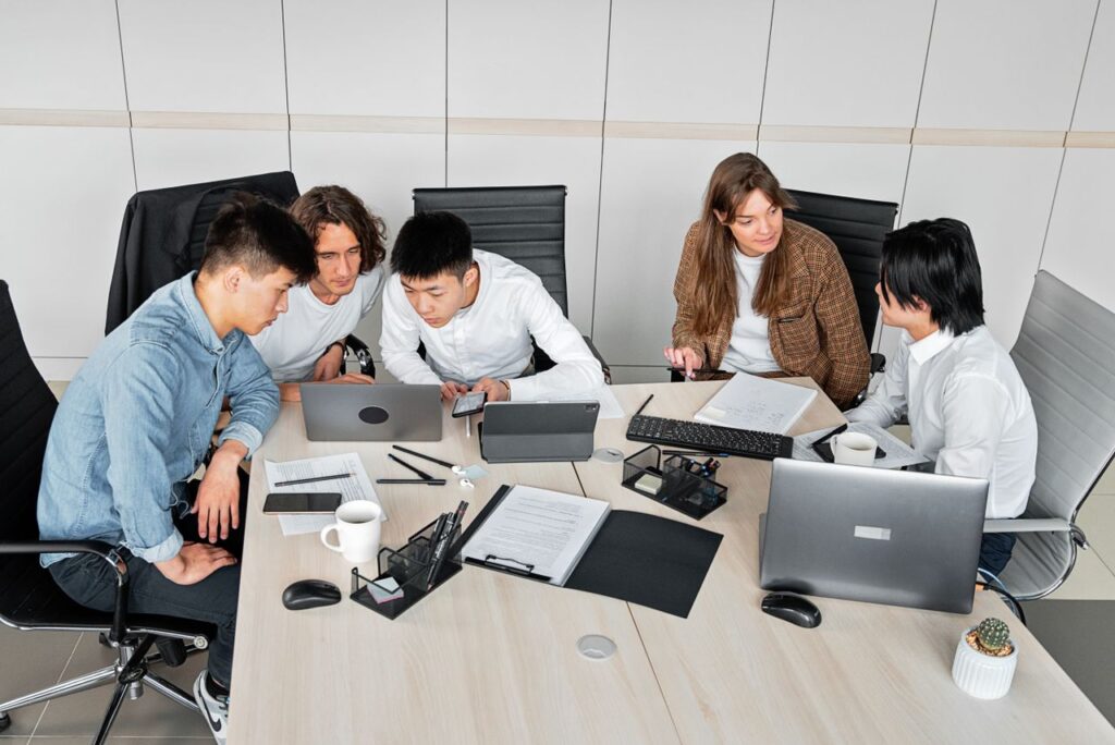pexels photo 7988674 A diverse group of colleagues working together in an office setting with laptops and documents.
